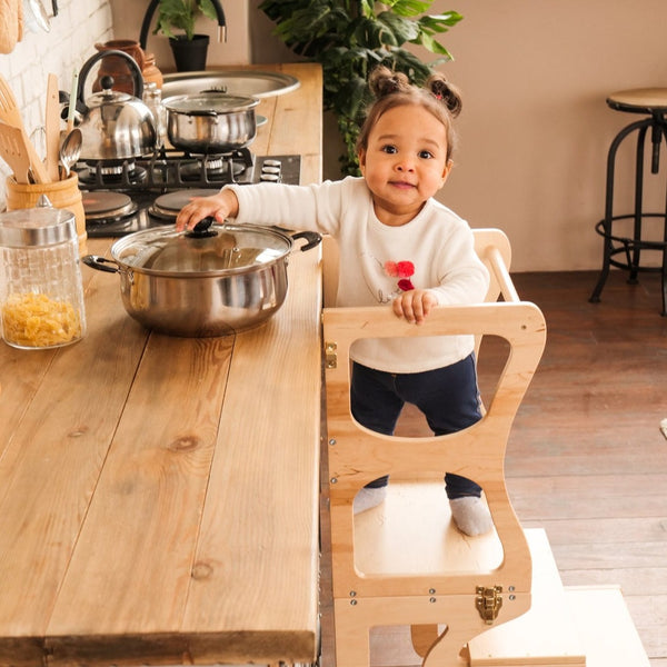 The child stands on a high chair and reaches the countertop. Kitchen step stool chair