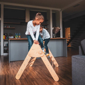 Two children are playing inside. Children's furniture  Pikler Triangle Color:  Naturally wood